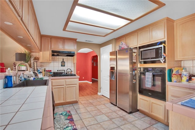 kitchen featuring appliances with stainless steel finishes, sink, light brown cabinets, and tile counters