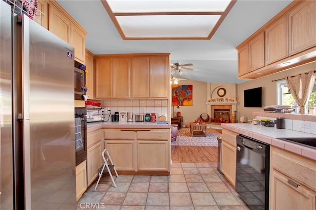 kitchen featuring tile countertops, black appliances, light brown cabinetry, and decorative backsplash