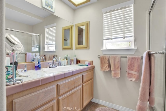 bathroom with a shower with door, vanity, and tile patterned flooring