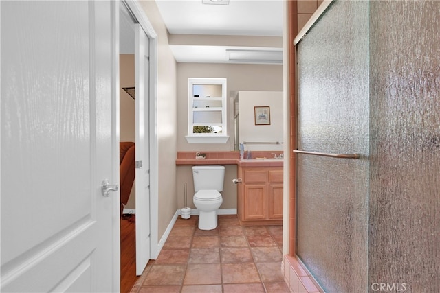 bathroom with toilet, a shower with shower door, vanity, and tile patterned floors