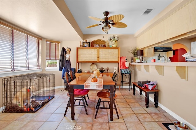 tiled dining room with ceiling fan and sink