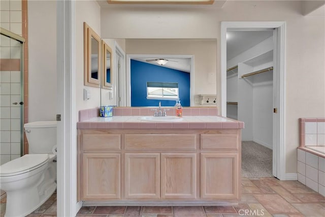 19848 Haida Rd, Apple Valley, CA 92307 - full bathroom with a tile shower, toilet, vanity, a walk in closet, and ceiling fan