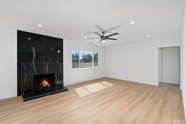 unfurnished living room with ceiling fan, light hardwood / wood-style floors, and a fireplace