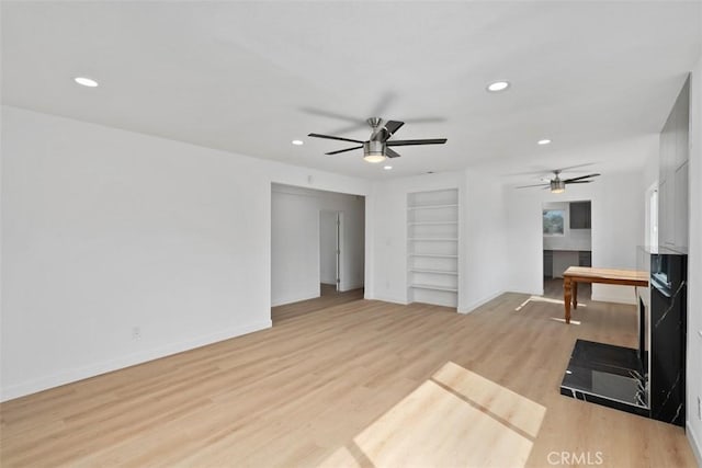 living room with ceiling fan, built in features, and light hardwood / wood-style flooring