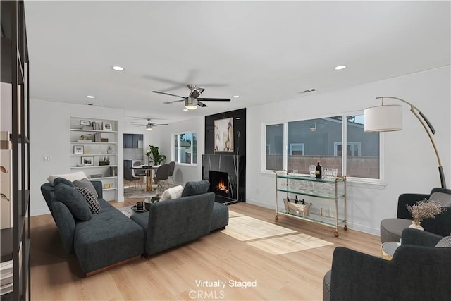 living room featuring ceiling fan, a healthy amount of sunlight, built in features, and hardwood / wood-style flooring