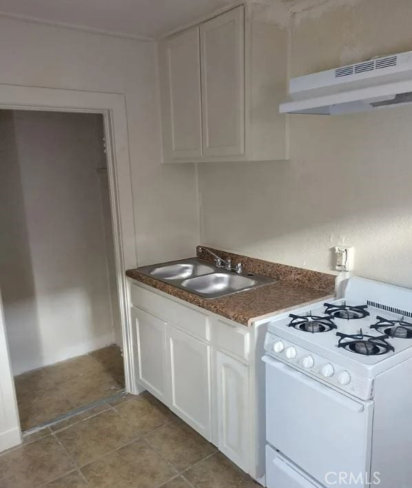 kitchen with white gas stove, sink, white cabinetry, range hood, and light tile patterned floors