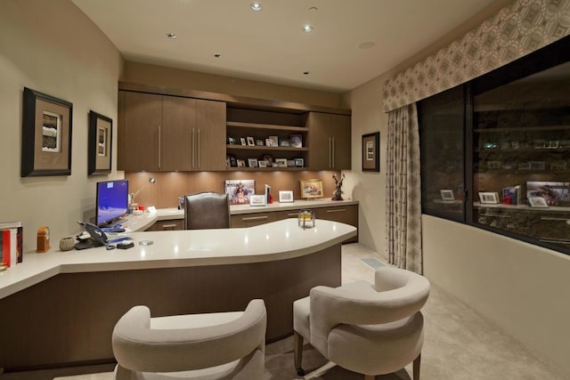 bar with built in desk, dark brown cabinetry, and light carpet