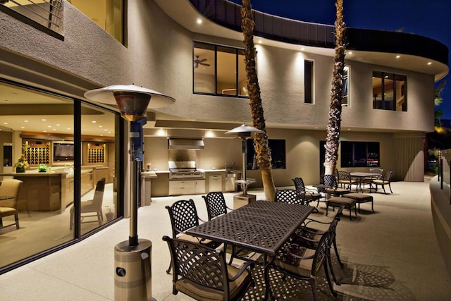 patio at night featuring an outdoor kitchen and area for grilling