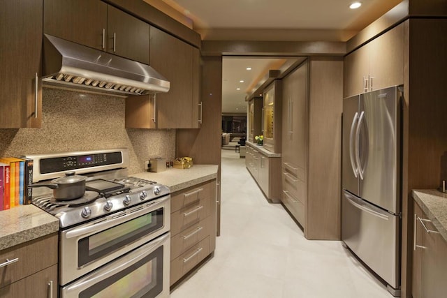 kitchen with light stone counters, backsplash, and appliances with stainless steel finishes