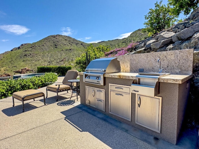 view of patio / terrace featuring area for grilling, a mountain view, and an outdoor kitchen