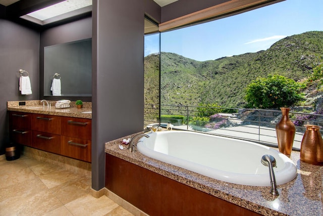 bathroom with a mountain view, tile patterned flooring, a washtub, and vanity