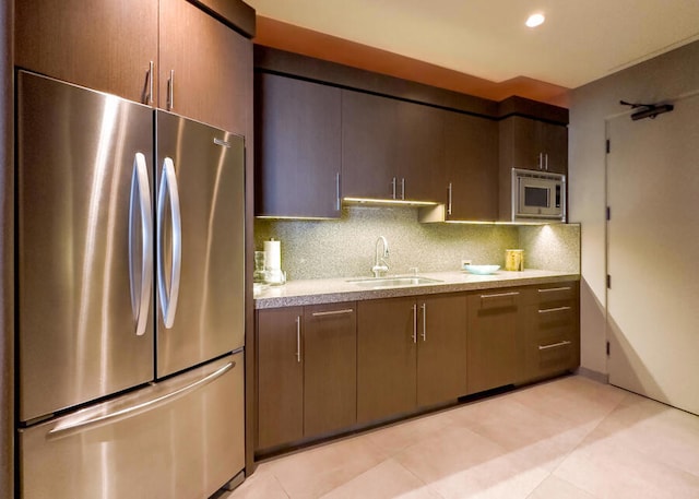 kitchen featuring sink, decorative backsplash, light tile patterned floors, and appliances with stainless steel finishes