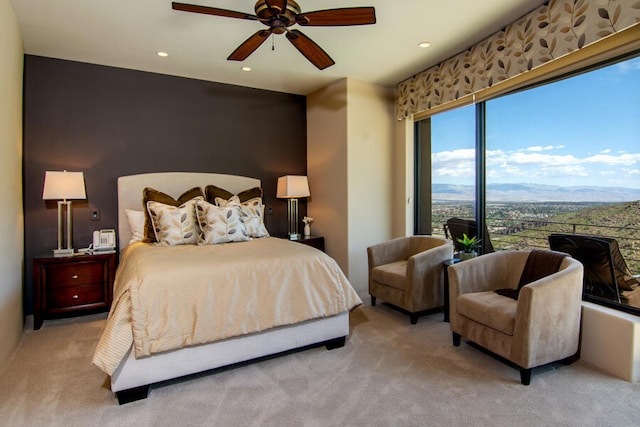 bedroom with light carpet, a mountain view, and ceiling fan