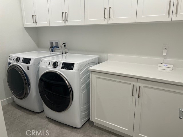 washroom featuring washing machine and clothes dryer, light tile patterned floors, and cabinets