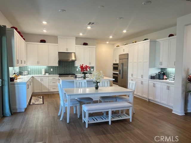 kitchen with extractor fan, white cabinetry, appliances with stainless steel finishes, and dark wood-type flooring