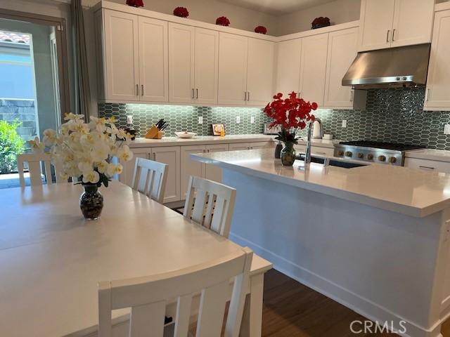 342 Sunrise Rd, Rancho Mission Viejo, CA 92694 - kitchen with a sink, tasteful backsplash, a center island with sink, light countertops, and under cabinet range hood