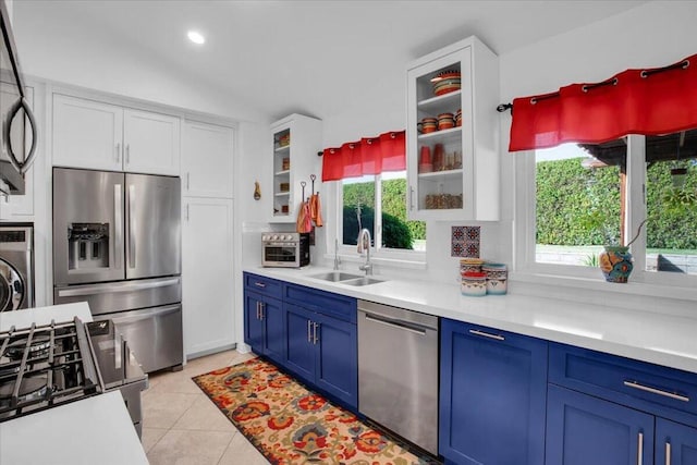 kitchen featuring stainless steel appliances, sink, white cabinets, light tile patterned floors, and blue cabinetry