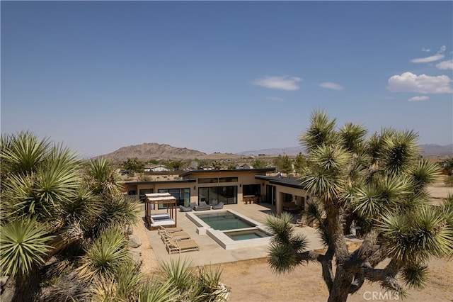 view of swimming pool featuring an in ground hot tub, a patio area, and a mountain view