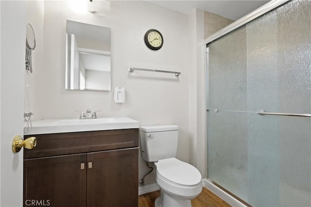 bathroom with hardwood / wood-style flooring, vanity, an enclosed shower, and toilet