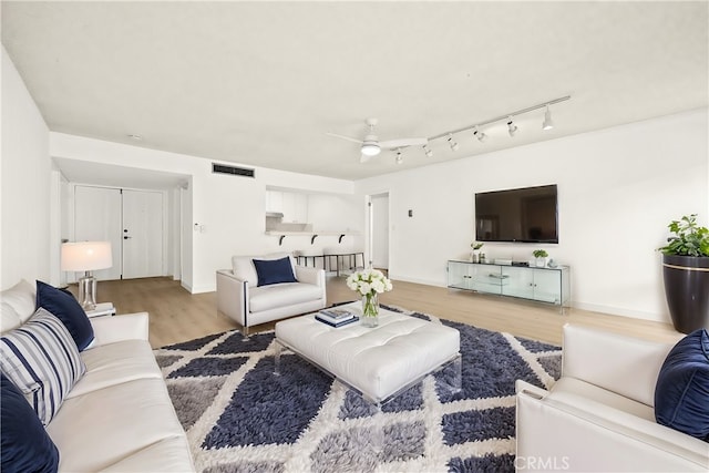 living room with ceiling fan and light hardwood / wood-style flooring