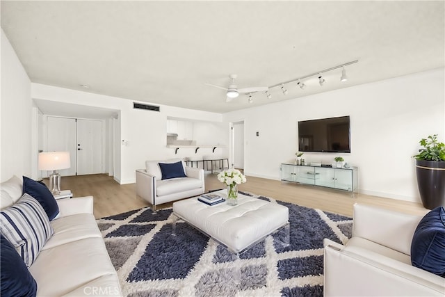 living room with a ceiling fan, baseboards, visible vents, and wood finished floors