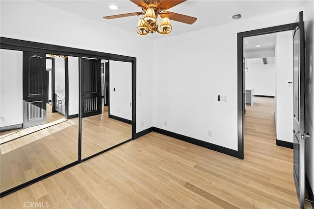 unfurnished bedroom featuring ceiling fan, light wood-type flooring, ensuite bathroom, and a closet