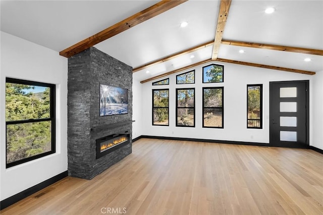 unfurnished living room featuring plenty of natural light, lofted ceiling with beams, and light wood-type flooring