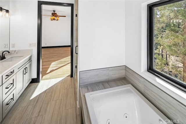 bathroom with hardwood / wood-style floors, vanity, ceiling fan, and a bathing tub