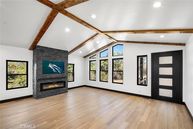 unfurnished living room with vaulted ceiling with beams, light hardwood / wood-style flooring, a healthy amount of sunlight, and a fireplace