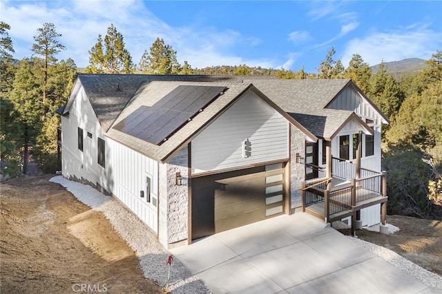 view of front of property featuring solar panels, covered porch, and a garage