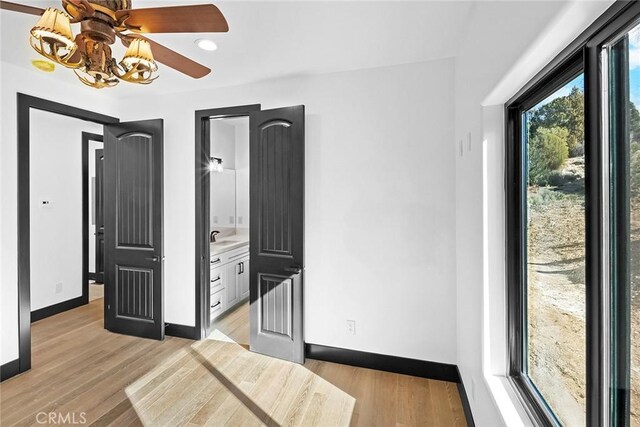 bedroom with light hardwood / wood-style floors, sink, connected bathroom, and a chandelier