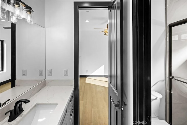 bathroom featuring walk in shower, hardwood / wood-style floors, vanity, and toilet