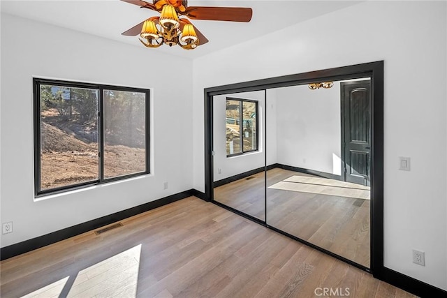 unfurnished bedroom with multiple windows, ceiling fan, a closet, and light wood-type flooring