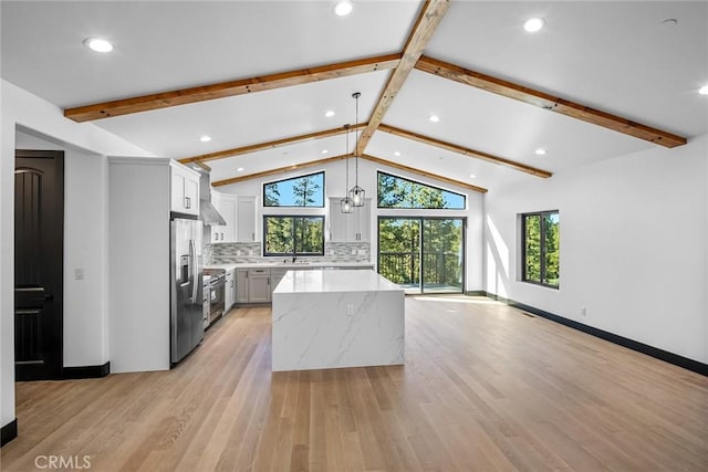 kitchen with lofted ceiling with beams, decorative backsplash, decorative light fixtures, light hardwood / wood-style floors, and stainless steel appliances