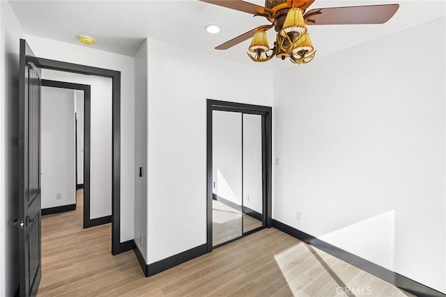 unfurnished bedroom with a closet, light hardwood / wood-style flooring, and ceiling fan with notable chandelier