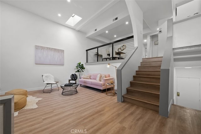 living room featuring light hardwood / wood-style floors and a skylight