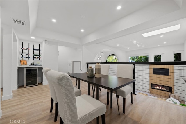 dining space with wine cooler, bar area, and light wood-type flooring