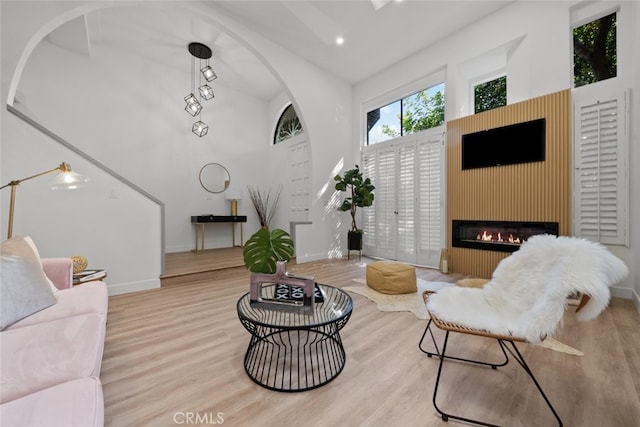 living room with a towering ceiling, light hardwood / wood-style flooring, and a fireplace