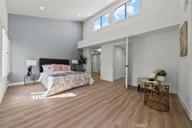 bedroom with light hardwood / wood-style flooring and a high ceiling