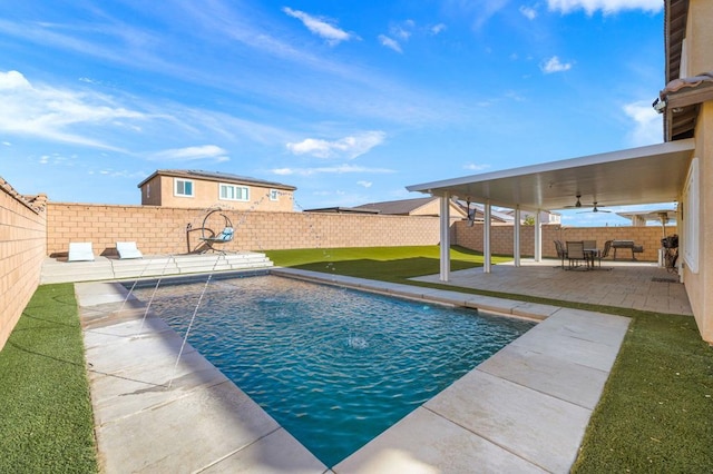 view of swimming pool featuring pool water feature, a patio, ceiling fan, and a lawn