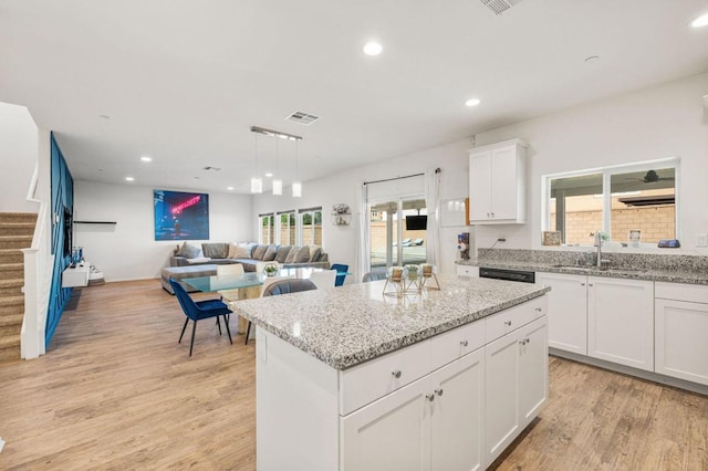 kitchen featuring white cabinets, a center island, light hardwood / wood-style floors, and a wealth of natural light