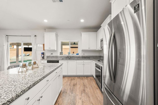 kitchen with plenty of natural light, white cabinets, and stainless steel appliances