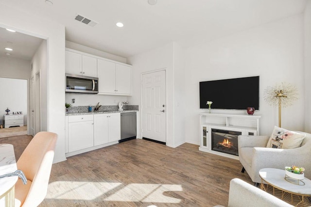 kitchen featuring white cabinetry, light hardwood / wood-style flooring, stainless steel appliances, and light stone counters