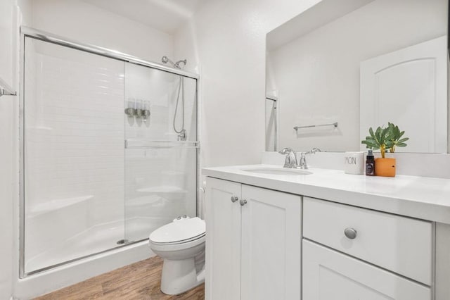 bathroom featuring vanity, wood-type flooring, an enclosed shower, and toilet