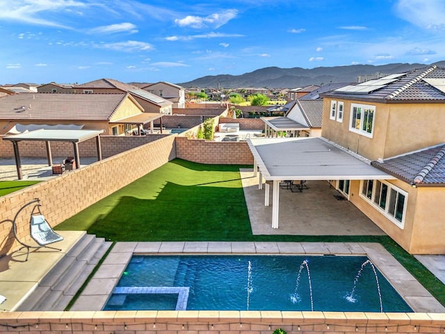 view of pool featuring pool water feature, a gazebo, a mountain view, a patio, and a lawn