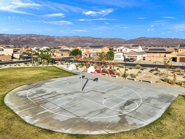 view of sport court with a mountain view and a yard