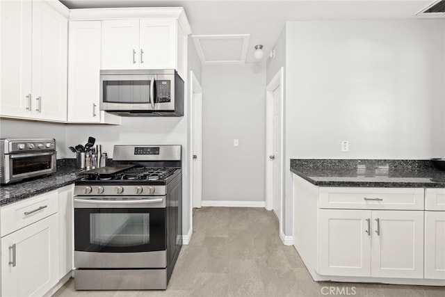 kitchen with appliances with stainless steel finishes, light wood-type flooring, white cabinets, and dark stone counters