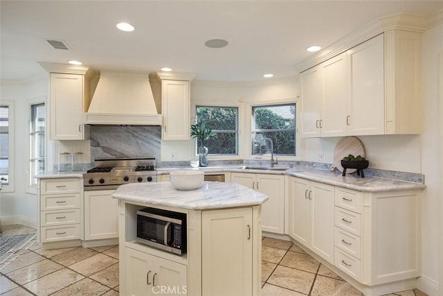 kitchen with a center island, crown molding, sink, light stone counters, and custom range hood