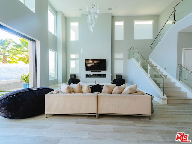 living room featuring a towering ceiling and light hardwood / wood-style flooring