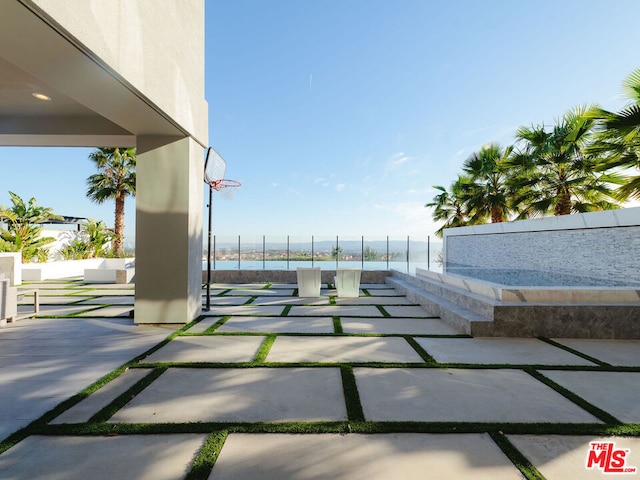 view of patio featuring basketball hoop and a water view